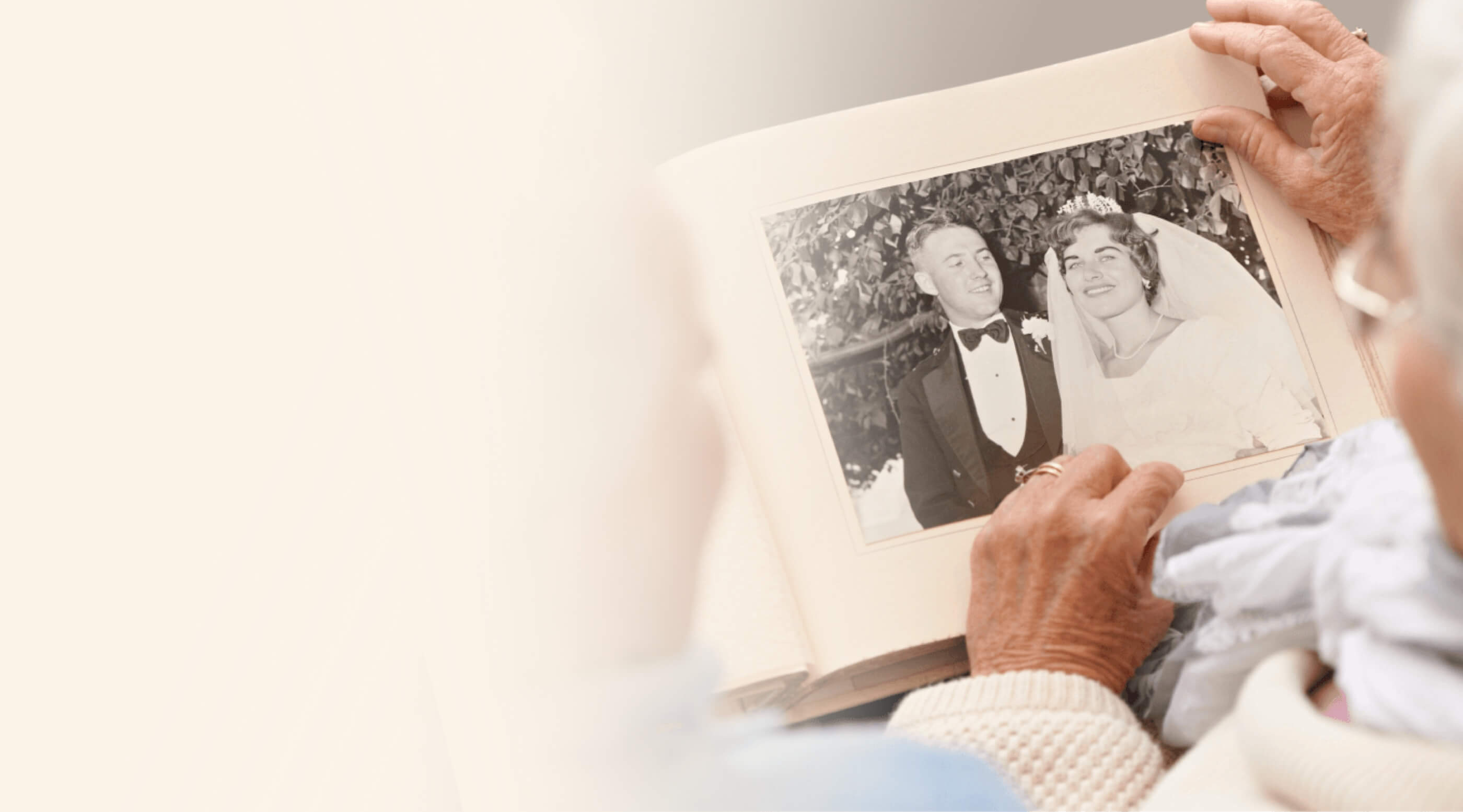 An elderly person holding an old wedding photo of a couple, with the photo showing them smiling on their wedding day