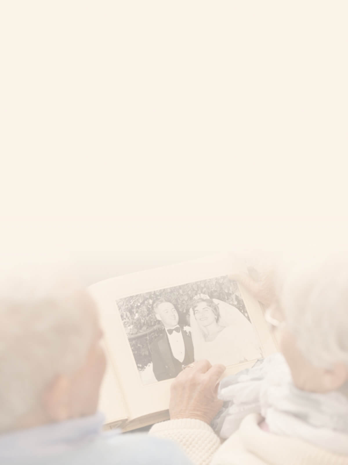 An elderly person holding an old wedding photo of a couple, with the photo showing them smiling on their wedding day.