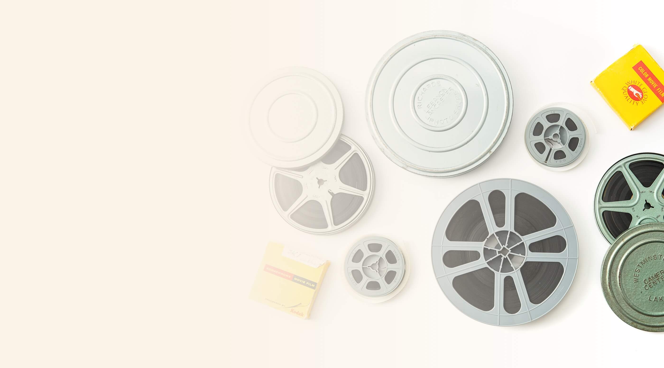 Vintage film reels in various sizes with old film canisters and a yellow box