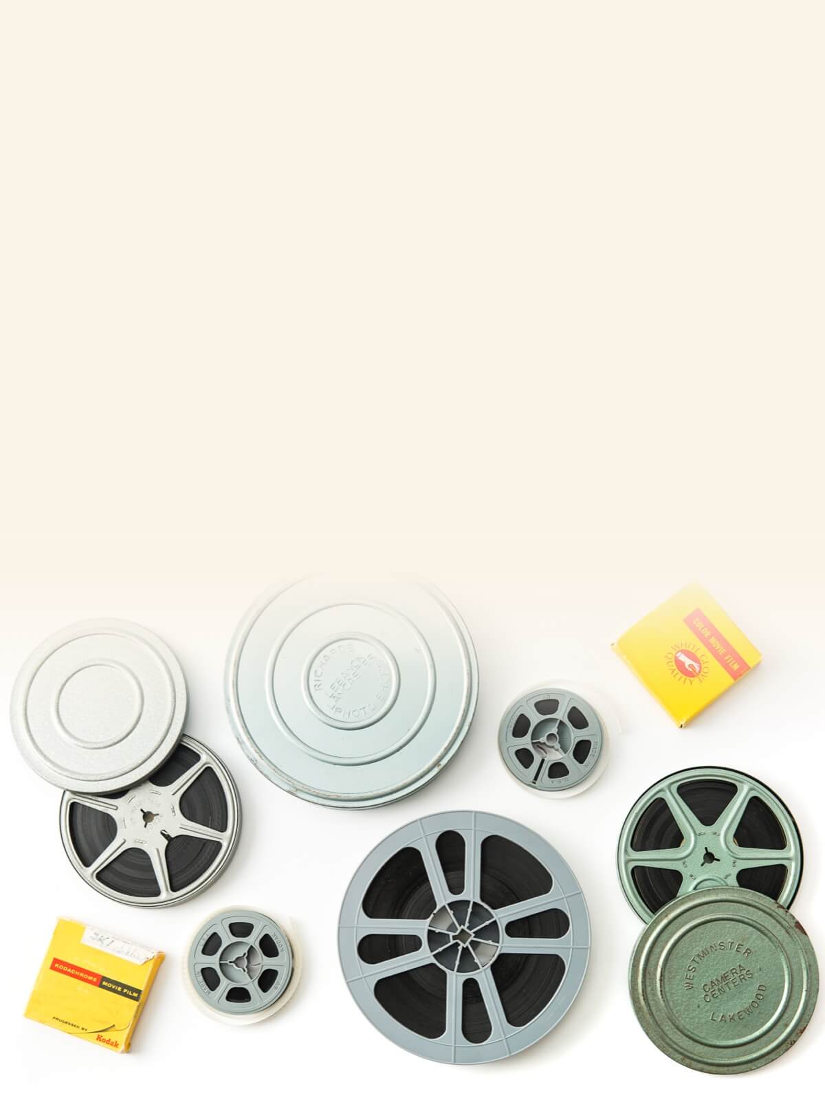 Close-up of vintage film reels in various sizes, with film canisters and a yellow box