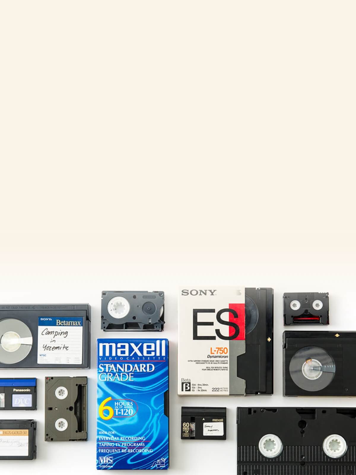 Collection of vintage video tapes including Betamax, VHS, and cassette tapes with packaging and labels on a white background.