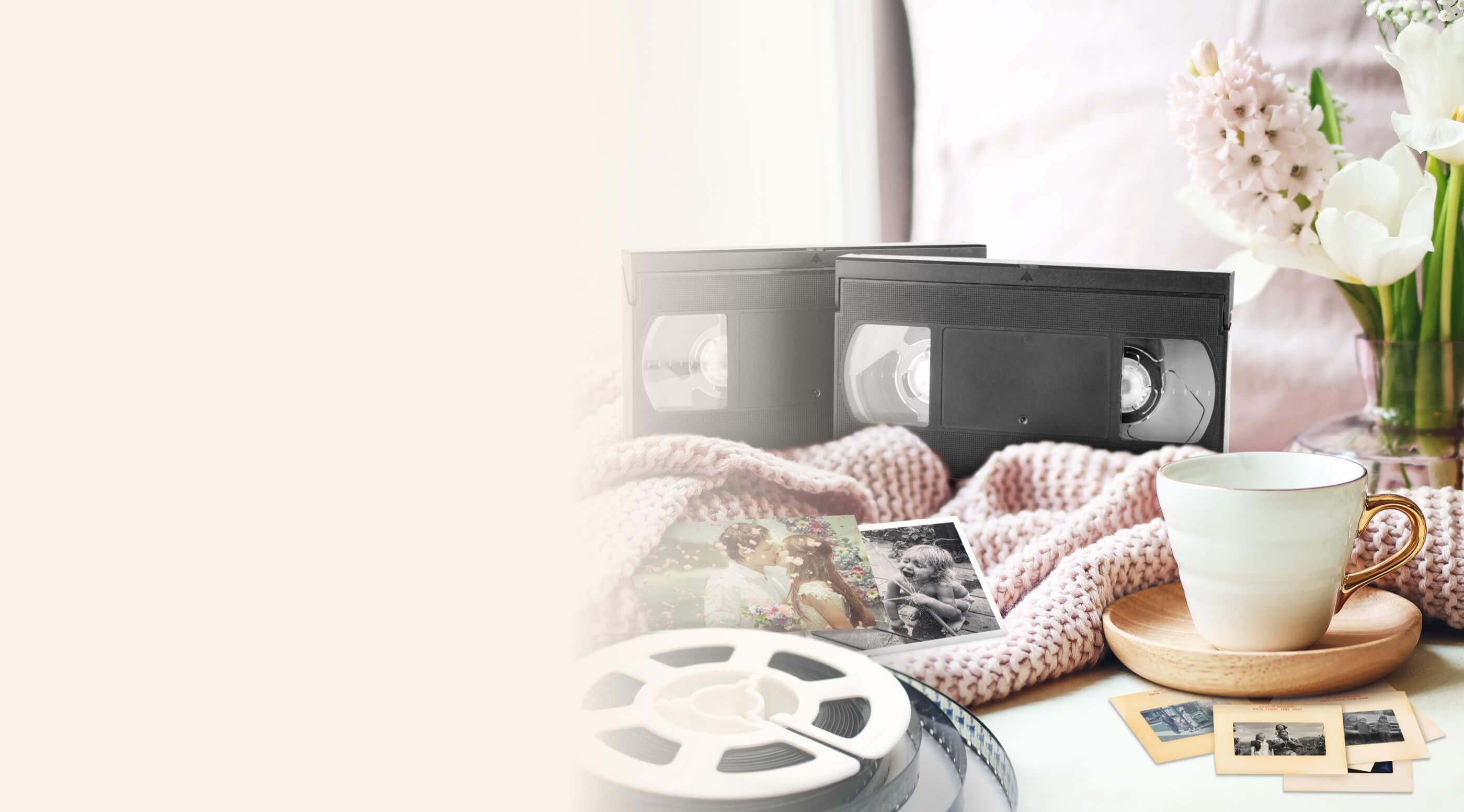 VHS tapes, vintage photographs, a cup of tea, and a flower vase on a cozy blanket
