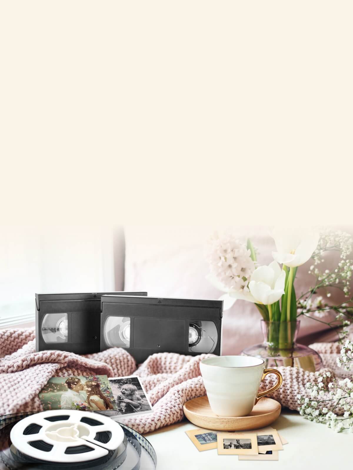 VHS tapes, vintage photographs, a cup of tea, and a vase of flowers on a cozy blanket
